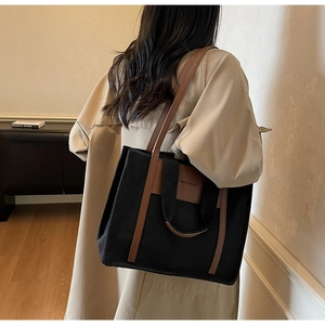 Detail view of canvas tote bag with brown leather straps shown on model side profile