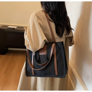 Macro detail of large canvas tote bag showing brown PU leather straps and black fabric