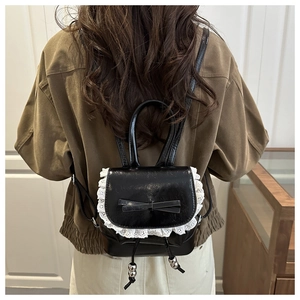 Close-up of ballet-style mini bucket backpack with white lace trim and bow on black leather