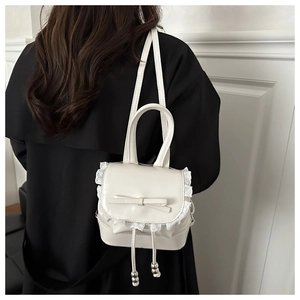 Rear view of a model wearing a cream mini backpack with lace and bow detailing