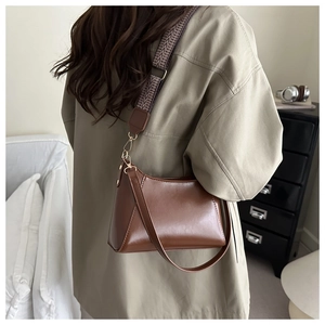 Detail of retro brown crossbody bag featuring dual straps and textured geometric strap