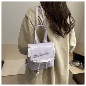 Detail of light purple mini backpack featuring lace trim, bow, and drawstring bead accents