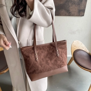 Detail view of brown tote bag with quilted suede and smooth leather stitching