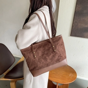 Detail of vintage brown suede tote bag with diamond quilting and gold rivets worn by model