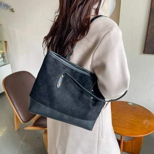 Close-up of black suede tote bag featuring diamond quilting and metal rivet details