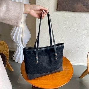 Detail of vintage quilted tote bag showing suede and leather texture on a wooden table