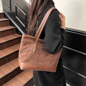 Detail view of brown suede tote bag featuring quilted texture and metallic rivets