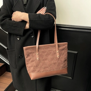 Detail of caramel brown quilted tote bag with matte texture and golden stud accents