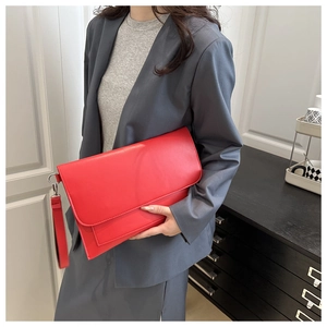 Close-up of red envelope clutch bag with detachable wrist strap and textured PU leather