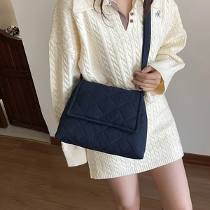 Navy blue quilted nylon crossbody bag with diamond stitch and black shoulder strap