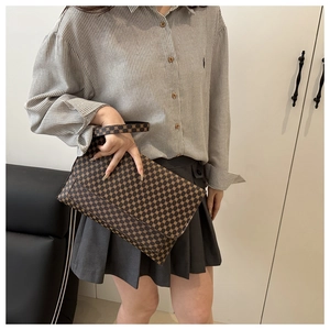 Detailed view of a vintage brown patterned envelope clutch with a short hand strap