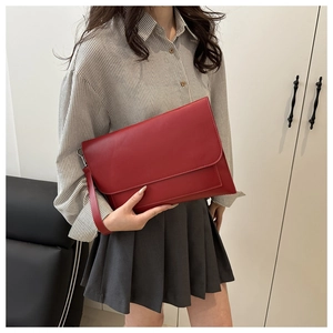 Detail of red leather envelope clutch bag with detachable wristlet and fine stitching