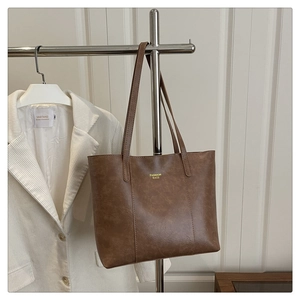 Detail of vintage brown leather tote bag showing fine texture and golden logo print