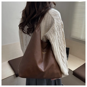 Detail view of large brown soft PU leather tote bag worn by model with fashion logo