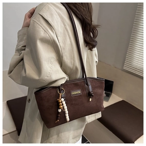 Detail of dark brown faux suede tote bag featuring a Fashion label and wood bead charm