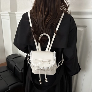 Chic cream mini backpack with lace trim and bow knot shown on model in black coat
