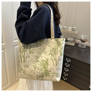 Detailed side view of canvas tote bag featuring green bamboo prints in home setting