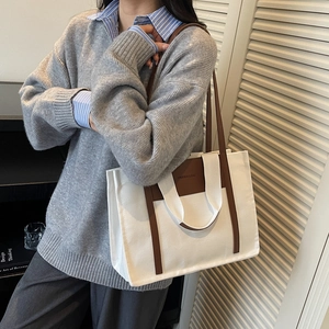 Minimalist canvas tote bag with brown leather handles and contrast trim for daily commute
