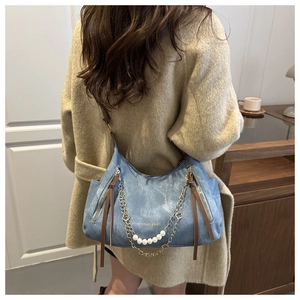 Détail du sac cabas en denim bleu avec perles, chaîne et longue tirette de fermeture
