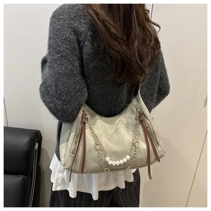 Detail view of a vintage shoulder bag with pearl chain decoration and brand text