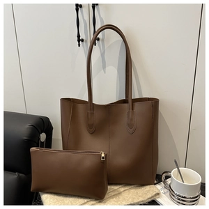Détail du sac cabas en cuir mat marron foncé avec pochette assortie sur tapis en maille