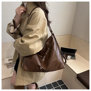 Detail of vintage brown leather tote bag showing soft texture and metal eyelet buckle strap