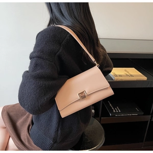 Detail of light pink shoulder bag featuring a rectangular gold metal clasp and leather flap