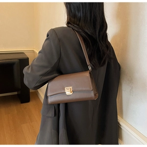 Detail of vintage brown baguette bag featuring a gold metal buckle and smooth leather finish