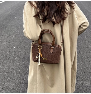 Gros plan d'un sac à bandoulière léopard avec texture mate et breloque en perles de bois