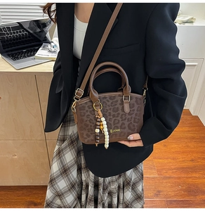 Mini borsa a sella leopardata con nappine di perline e tracolla indossata da una modella