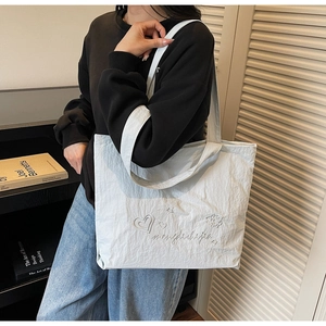 Détail d'un grand sac cabas bleu clair en tissu froissé avec broderie blanche