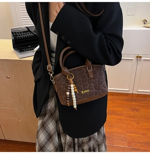 Detail of leopard print handbag with beaded charm and adjustable strap on model