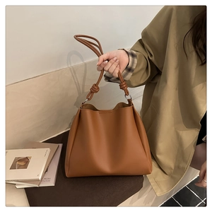 Detail of a brown leather tote bag showing a unique knotted handle design for women