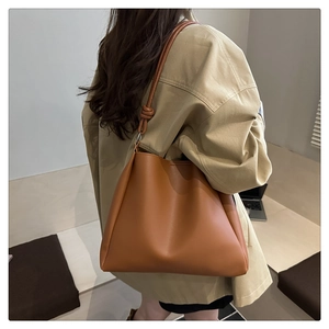 Close-up of caramel brown PU leather bucket bag featuring a unique knotted shoulder strap