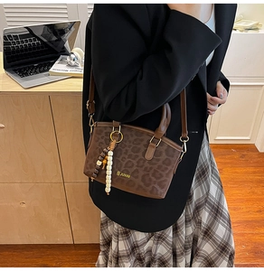 Leopard print crossbody bag with beaded charms in a professional office setting view