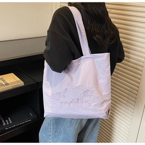 Détail d'un cabas en toile lilas avec broderie en forme de cœur et bandoulière souple