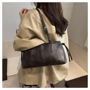 Detailansicht einer dunkelbraunen Vintage-Schultertasche aus Kunstleder mit Zierkordeln