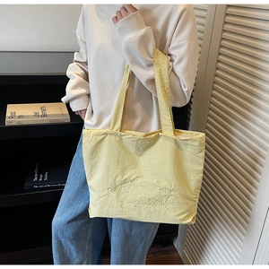 Vue détaillée du sac cabas en nylon jaune avec broderie cœur et étoile et lettrage
