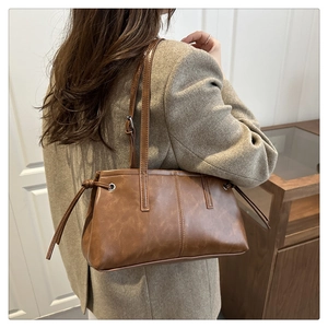 Close-up of vintage brown leather shoulder bag with drawstring detail on female model