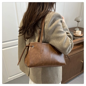 Braune Vintage-Schultertasche aus Kunstleder mit Kordelzug-Details am Model getragen