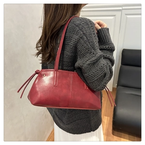 Detailansicht der tiefroten Ledertasche an einem Model mit minimalistischem Quastenknoten