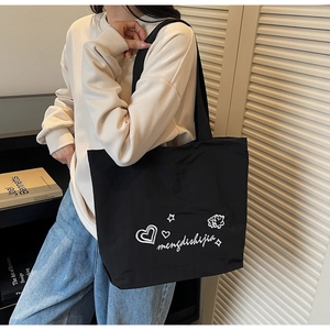 Close-up of black canvas tote bag with white graphic print worn by a model