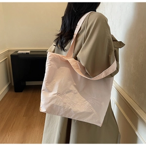 Detailed view of light pink tote bag featuring exquisite embroidery and soft texture