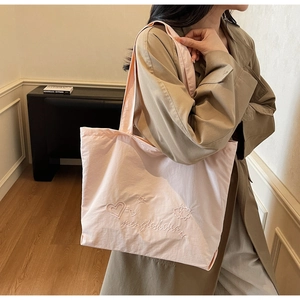 Detail of light pink canvas tote bag featuring premium heart and star embroidery work