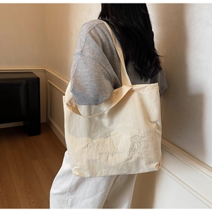 Detail of the high-quality cotton canvas texture and delicate embroidery on the tote bag
