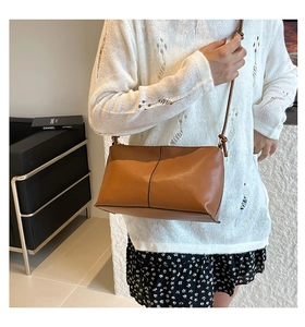 Detail of brown leather shoulder bag with vertical seam and knotted strap design