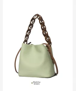 Detail of matcha green bucket bag with lychee grain leather and brown chain strap