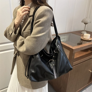 Elegant large black faux leather tote bag with metal buckle shown on a model in an office setting