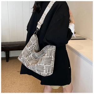 Detail of geometric woven tote bag with wide jacquard strap and textured fabric