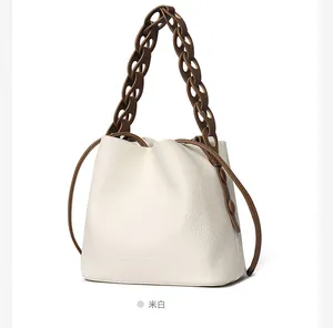 Detail of off-white leather bucket bag with chunky brown chain and drawstring closure